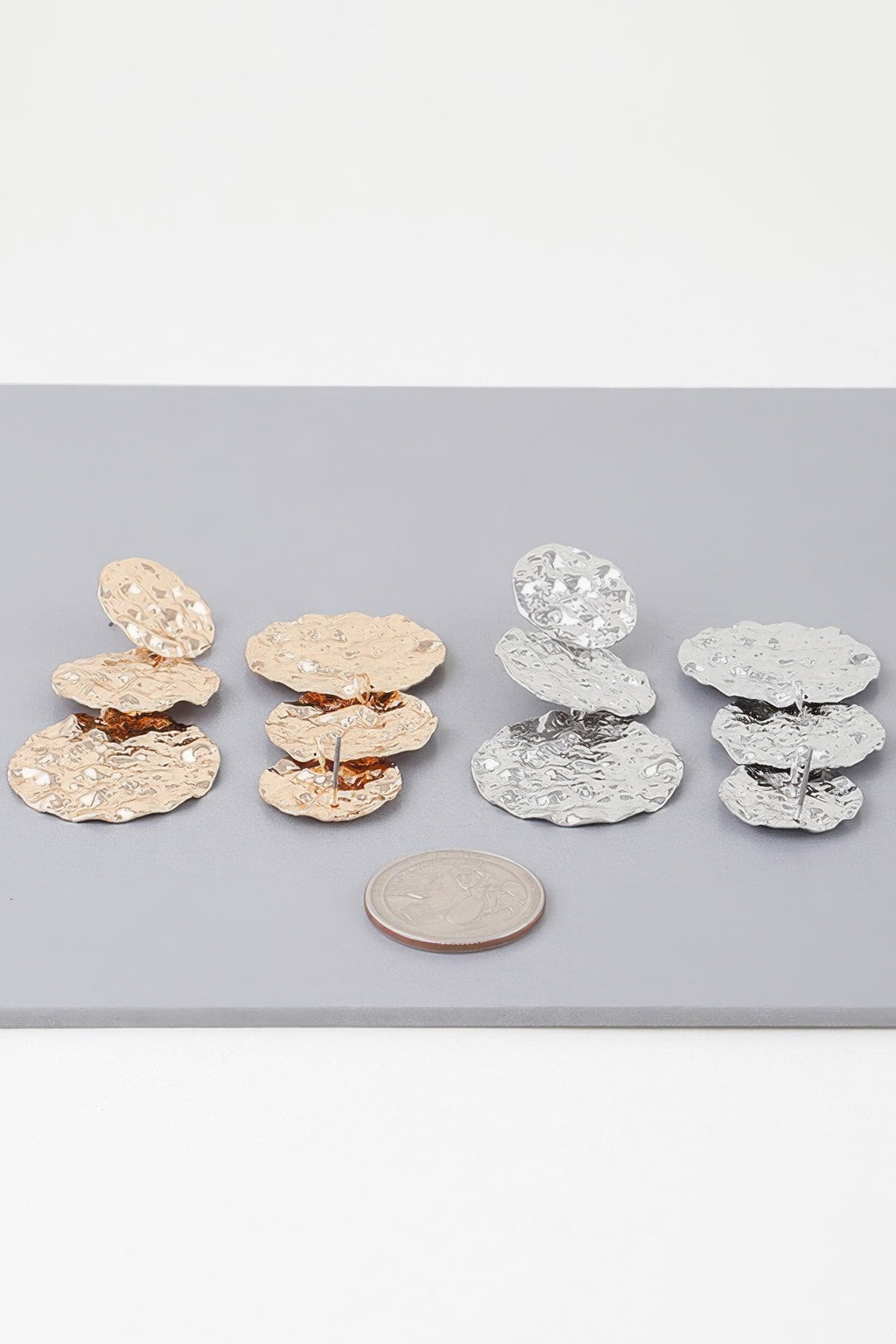 Gold and silver triple hammered disc earrings shown together, each with three discs