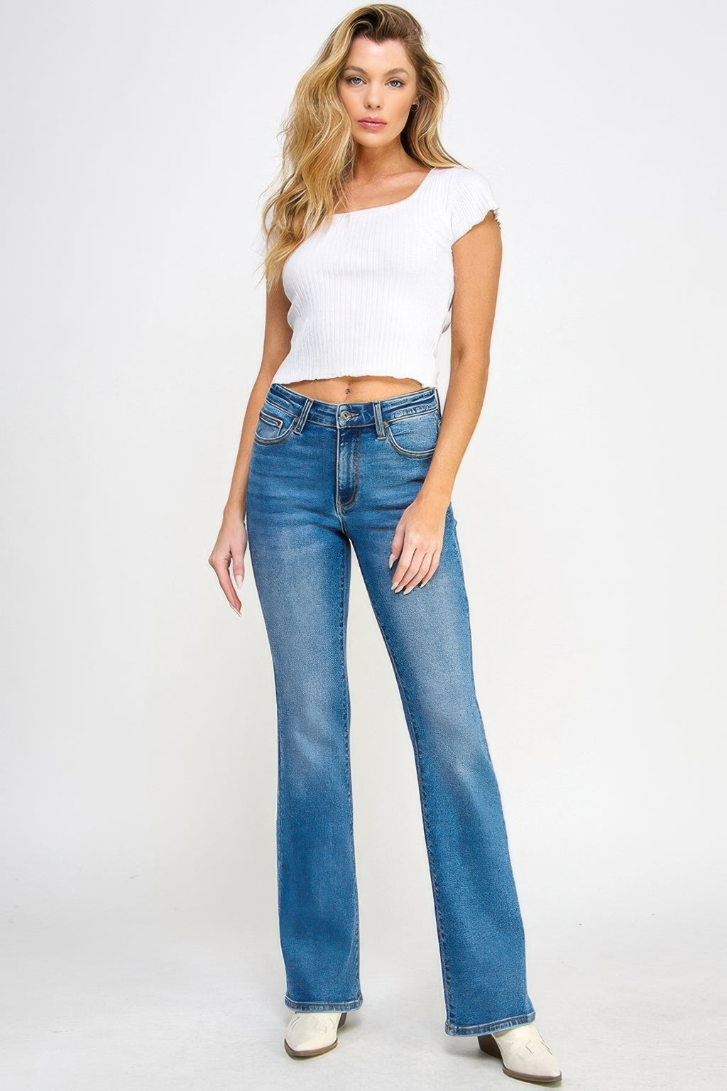 Jeans azul tiro medio con control de abdomen, bota acampanada y costuras frontales