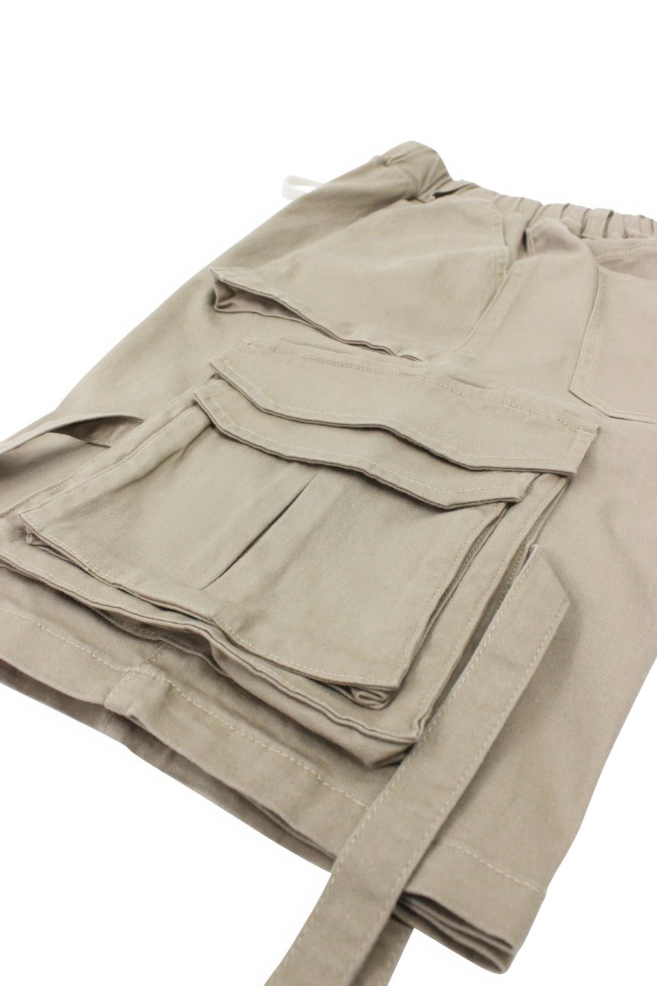 Beige twill cargo shorts with layered flap pockets and visible stitched seams