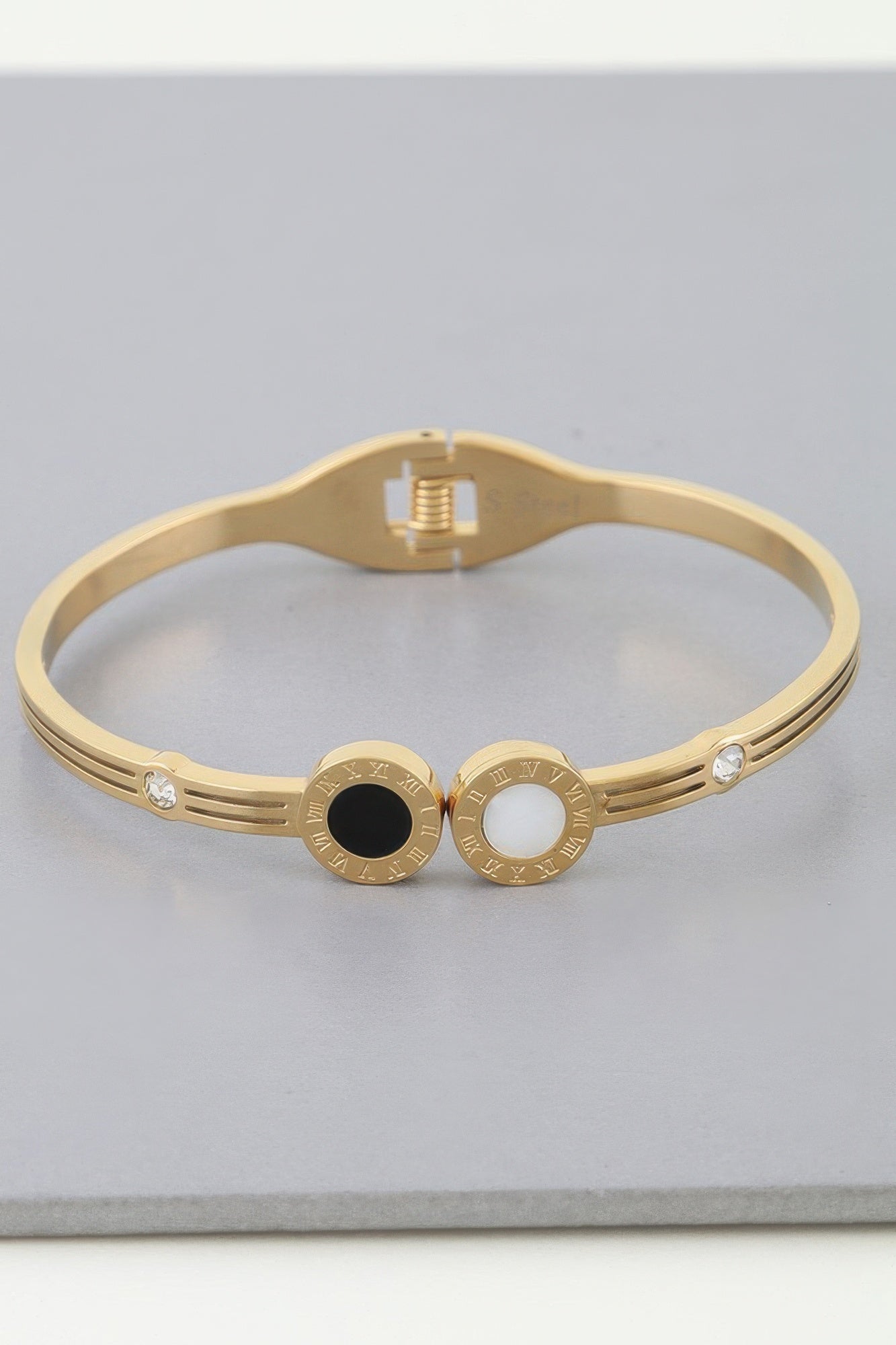 Gold-tone wrap bracelet with twin clock dials, black and white center details