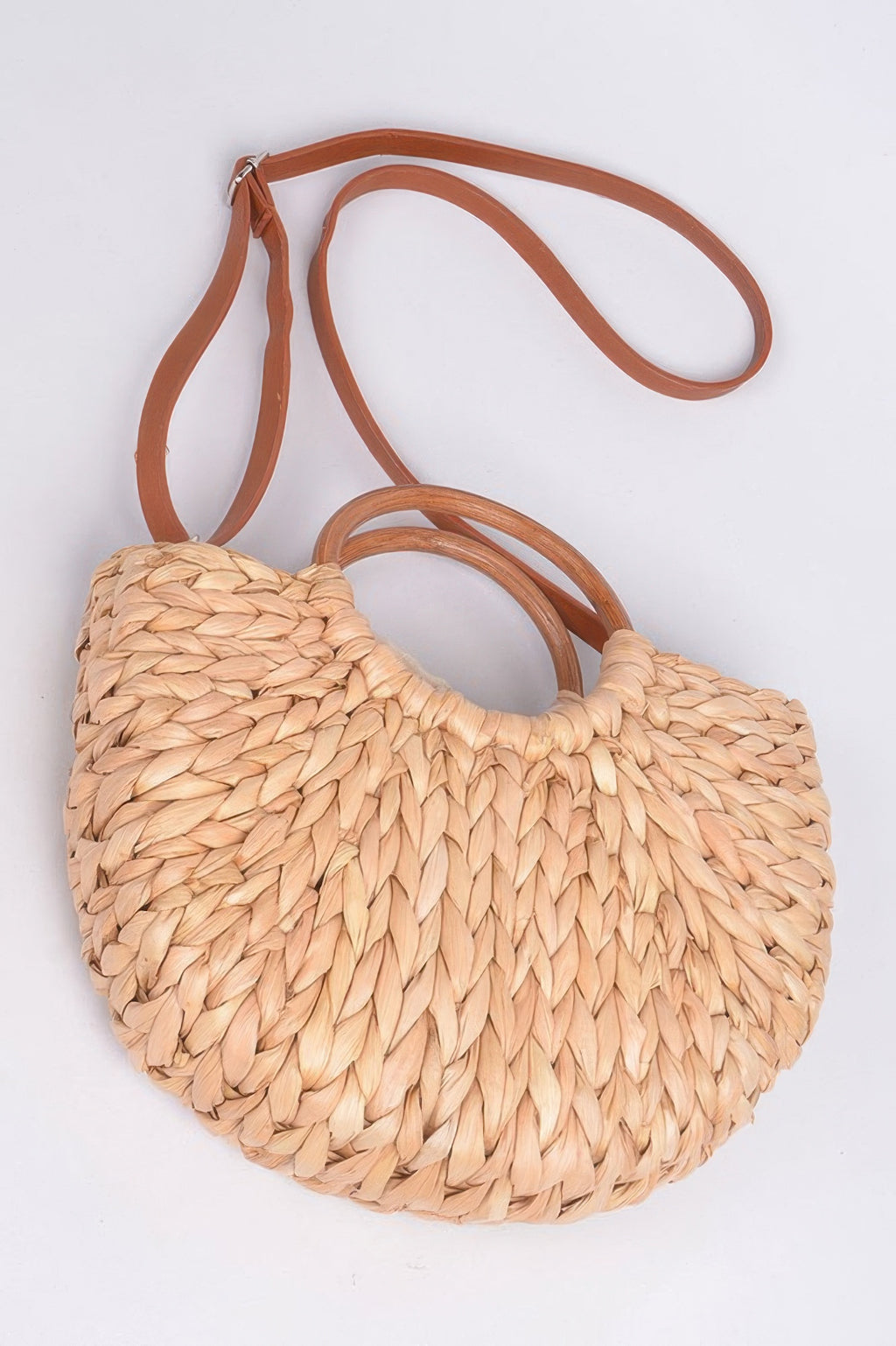 Natural half-moon woven clutch with twist handle detail and tan crossbody strap.
