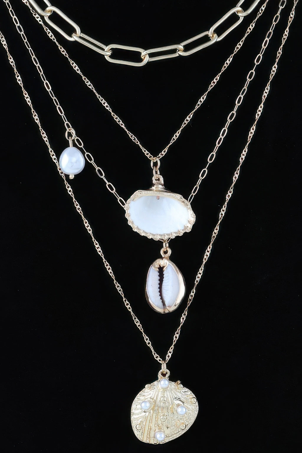 Gold-tone layered charm necklace with white shell charm, blue oval bead, and coin charm