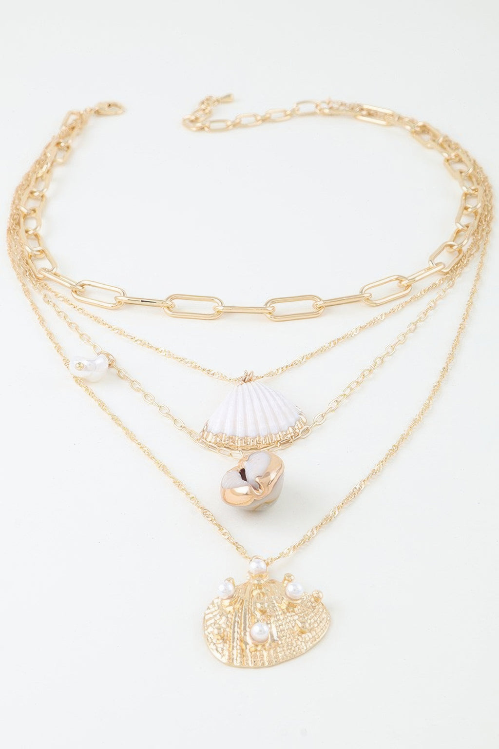 Charm chain necklace set with three gold-tone layers and seashell, round coin, and pearl details