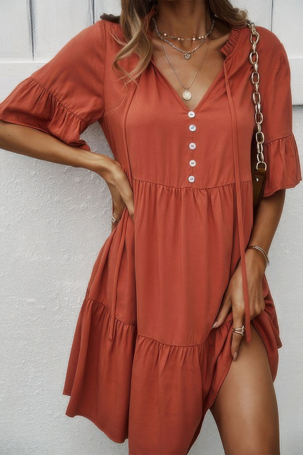 Orange V-neck ruffle hem dress with button front and tiered skirt, short flounce sleeves.