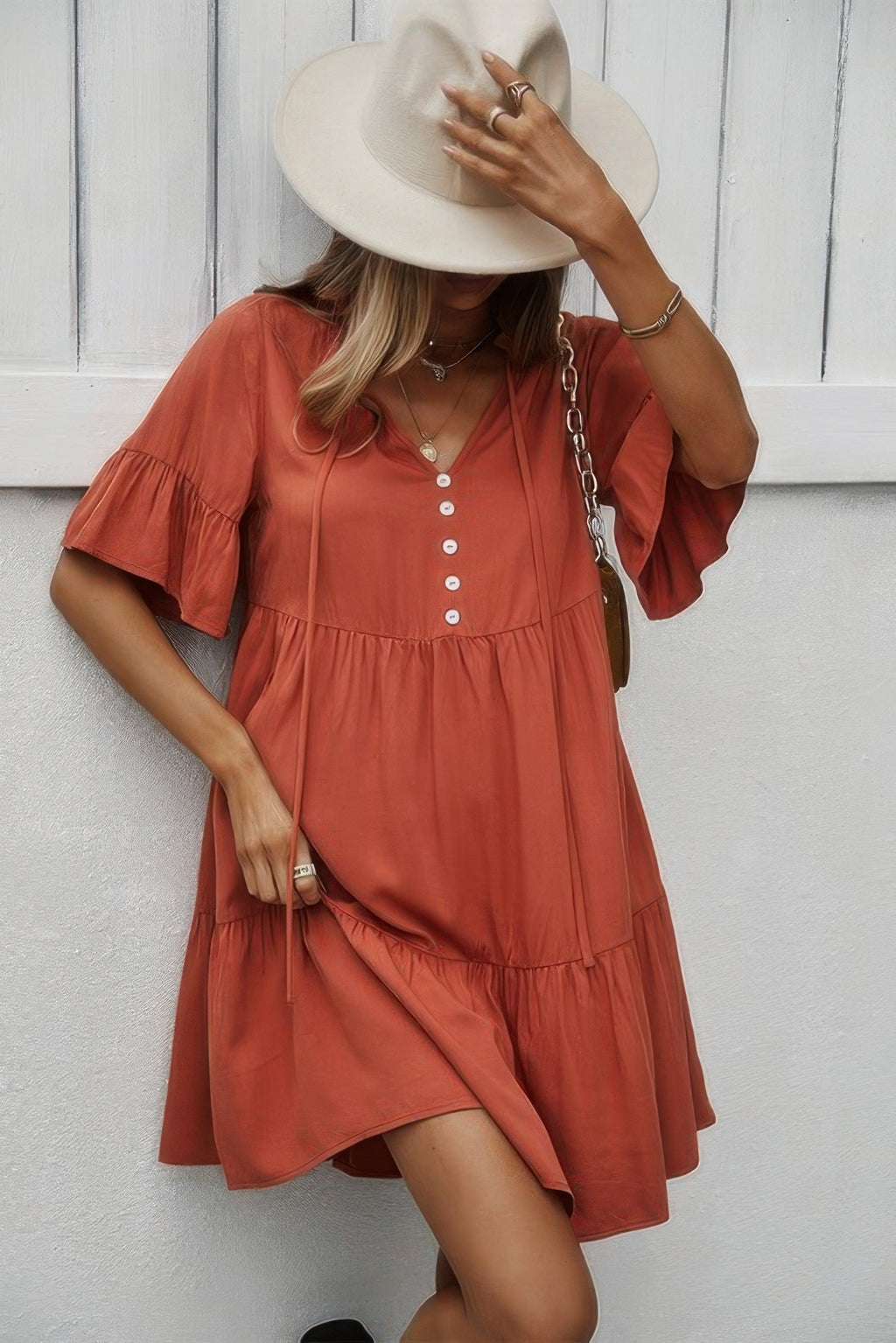 Orange V-neck button dress with tiered ruffle layers and flounce sleeves, uneven hemline.