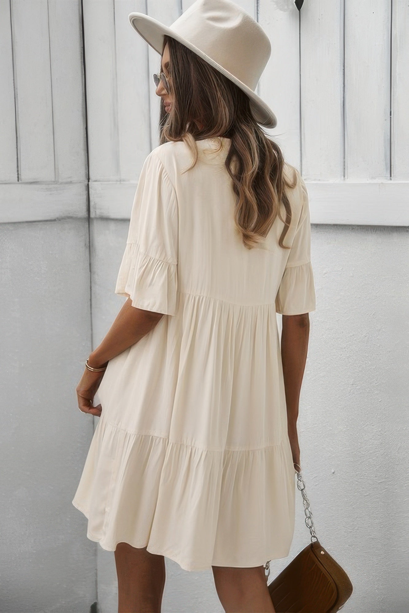 Cream V-neck button dress with tiered ruffle skirt and short flounce sleeves, back view.