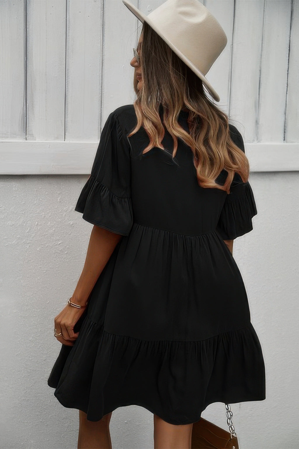 Black V-neck button dress with tiered ruffle skirt and short flounce sleeves, side/back view.