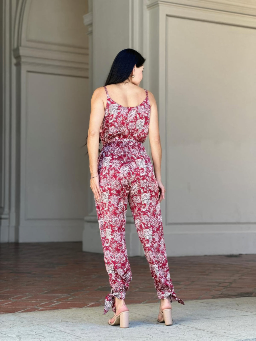 Side view of V-neck sleeveless paisley jumpsuit with tie waist