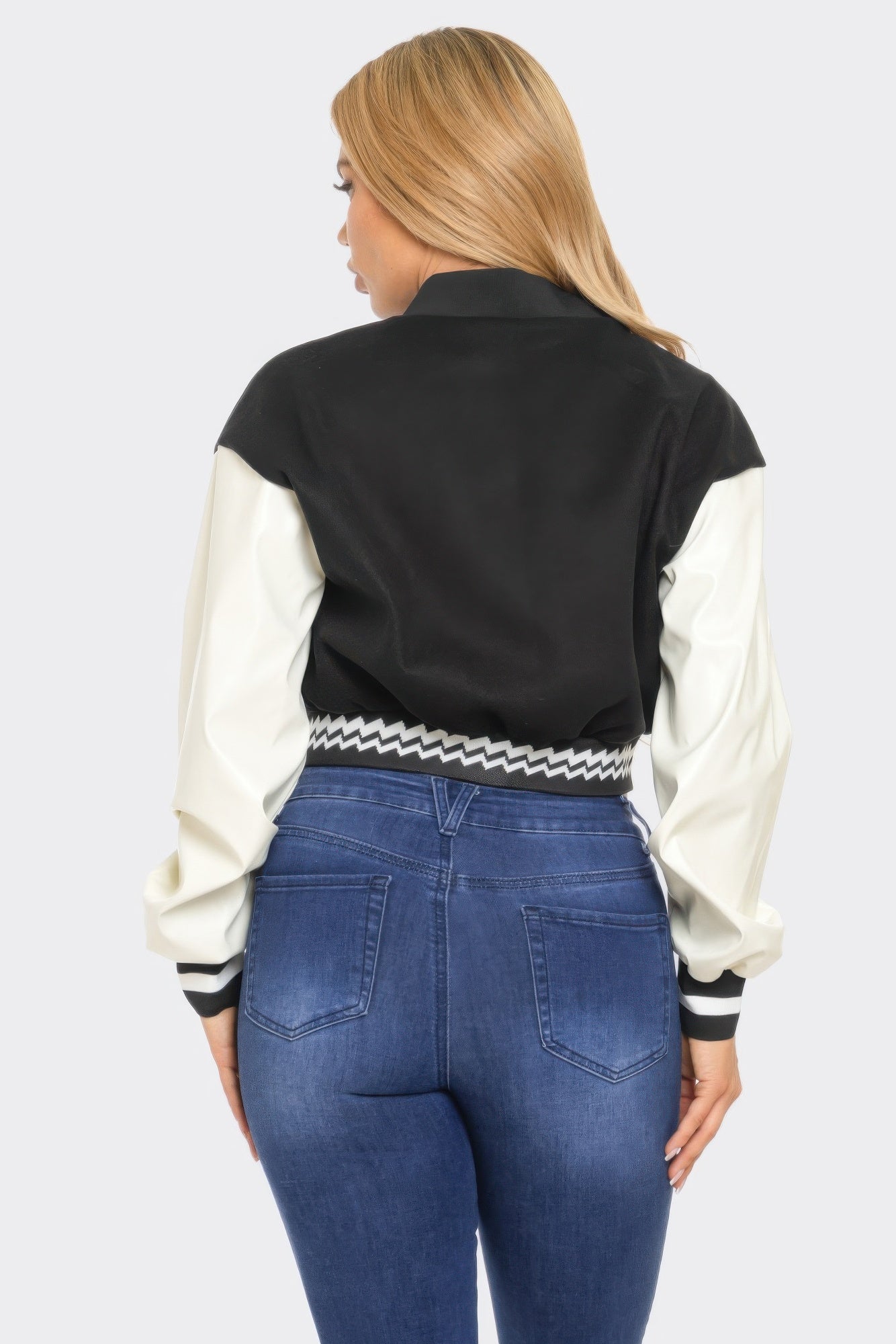 Back view of varsity patchwork Y2K jacket, black back panel, off-white sleeves, striped trim