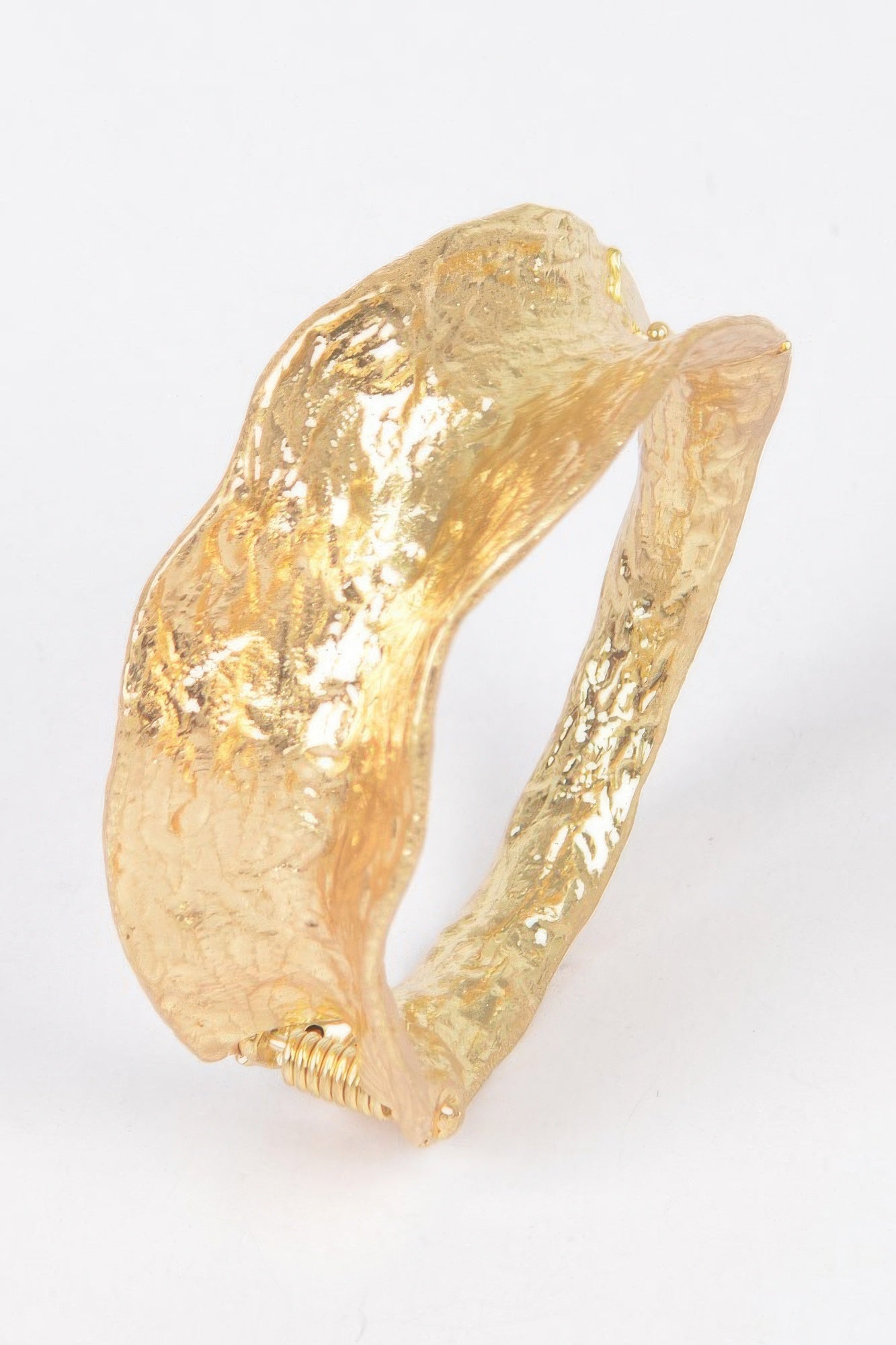 Gold cuff bracelet angled view, textured metal with ridged clasp ends
