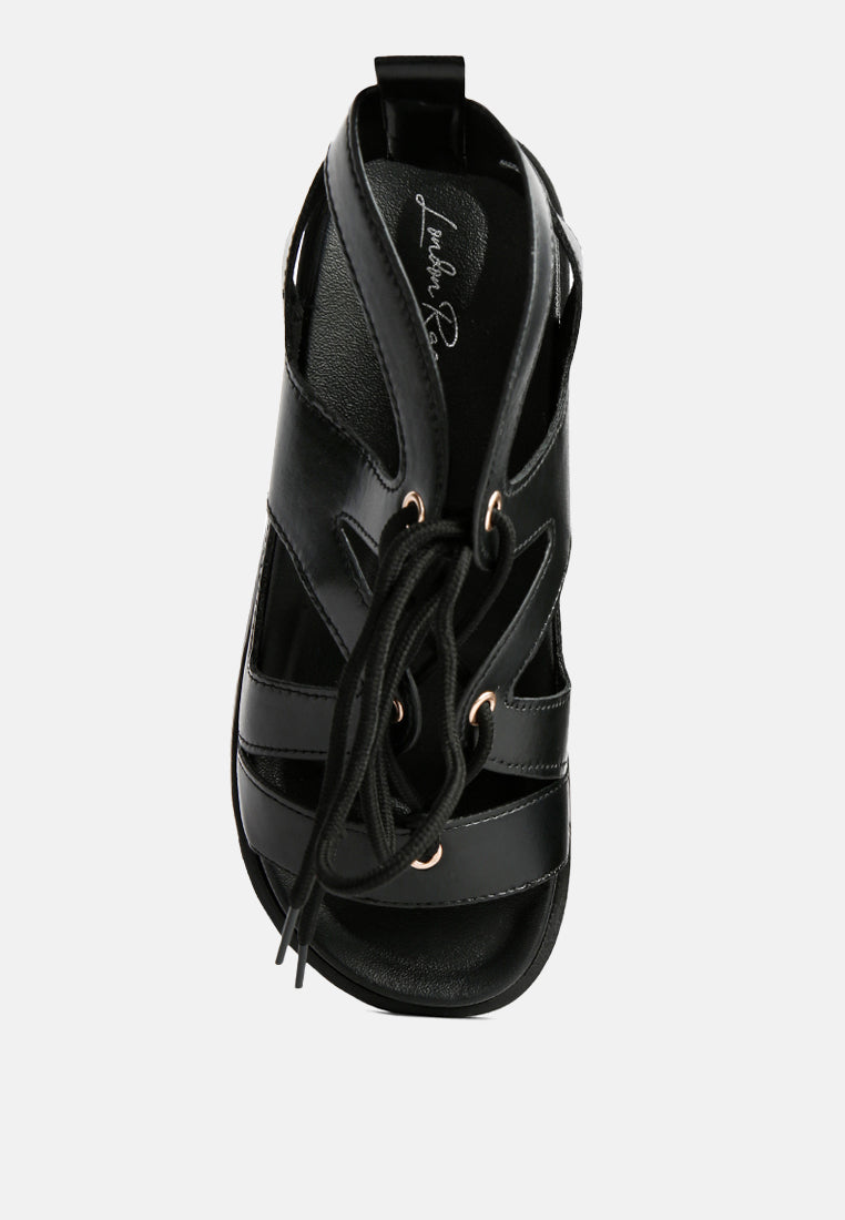 Black flat sandals with lace-up front and padded heel opening