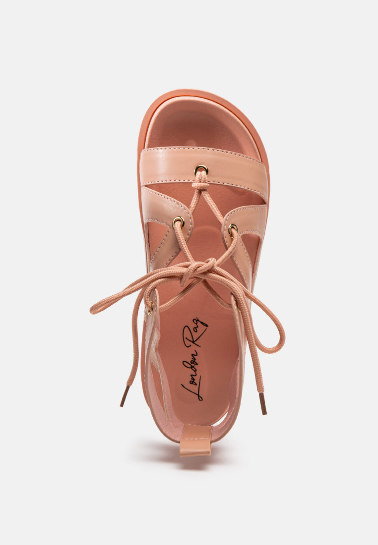 Pink sandal with lace-up ties, ankle-high opening, and padded footbed