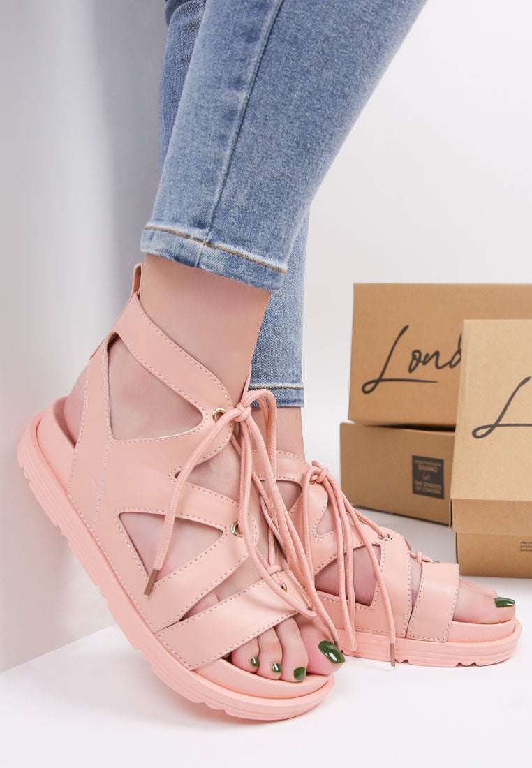 Pink tie-up flat sandals with crisscross laces and openwork toe