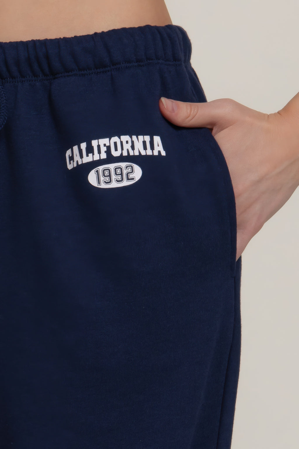 Close-up of True navy sweatpants with “CALIFORNIA 1992” printed logo on waistband area