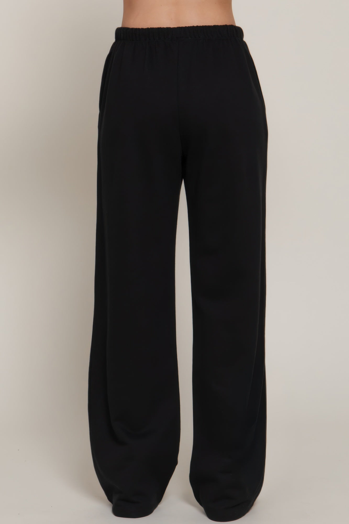 Black sweatpants back view with elastic waistband and wide straight legs