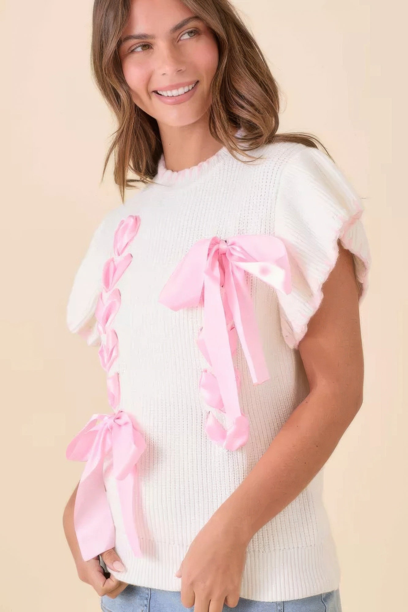 Ivory knit sweater top with pink ribbon bow accents at front
