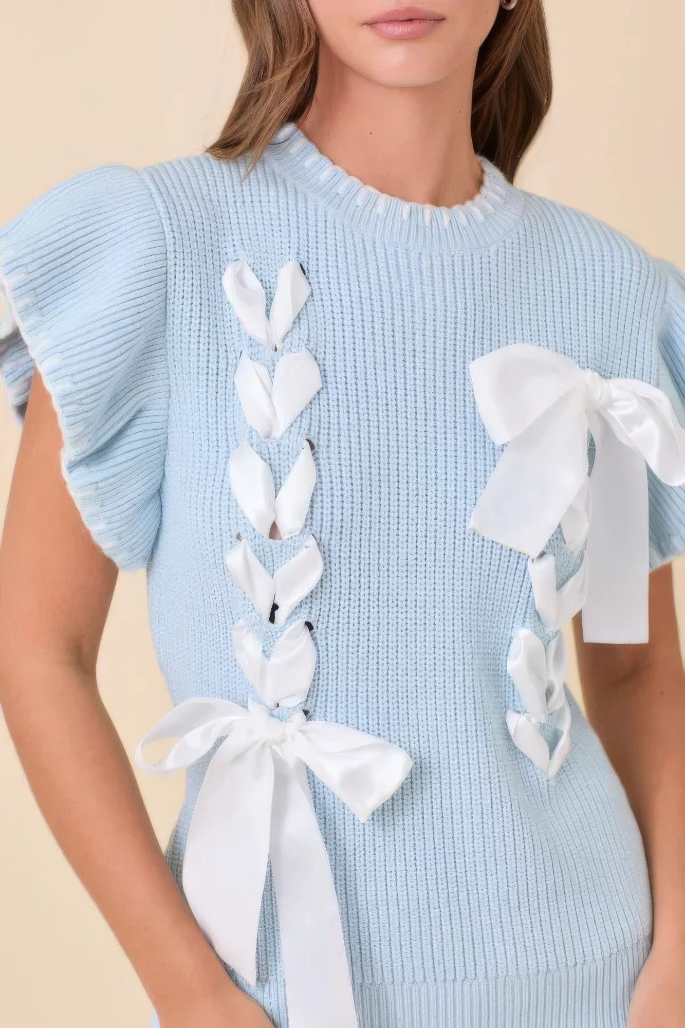 Light blue ribbed knit sweater with white ribbon bow trim on shoulders and chest