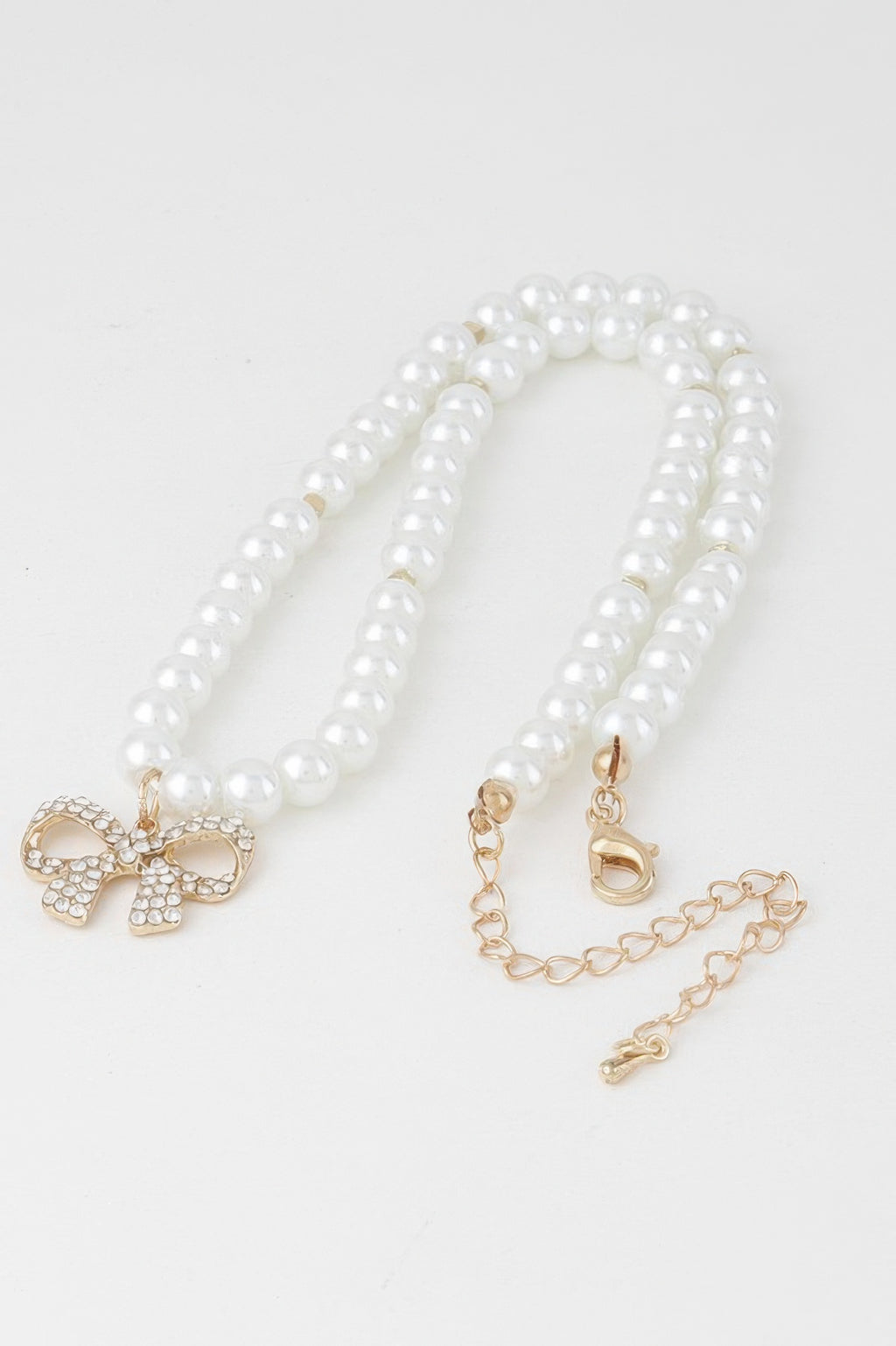 White pearl bow necklace set with pearl strands, gold-tone bow charm and clasp