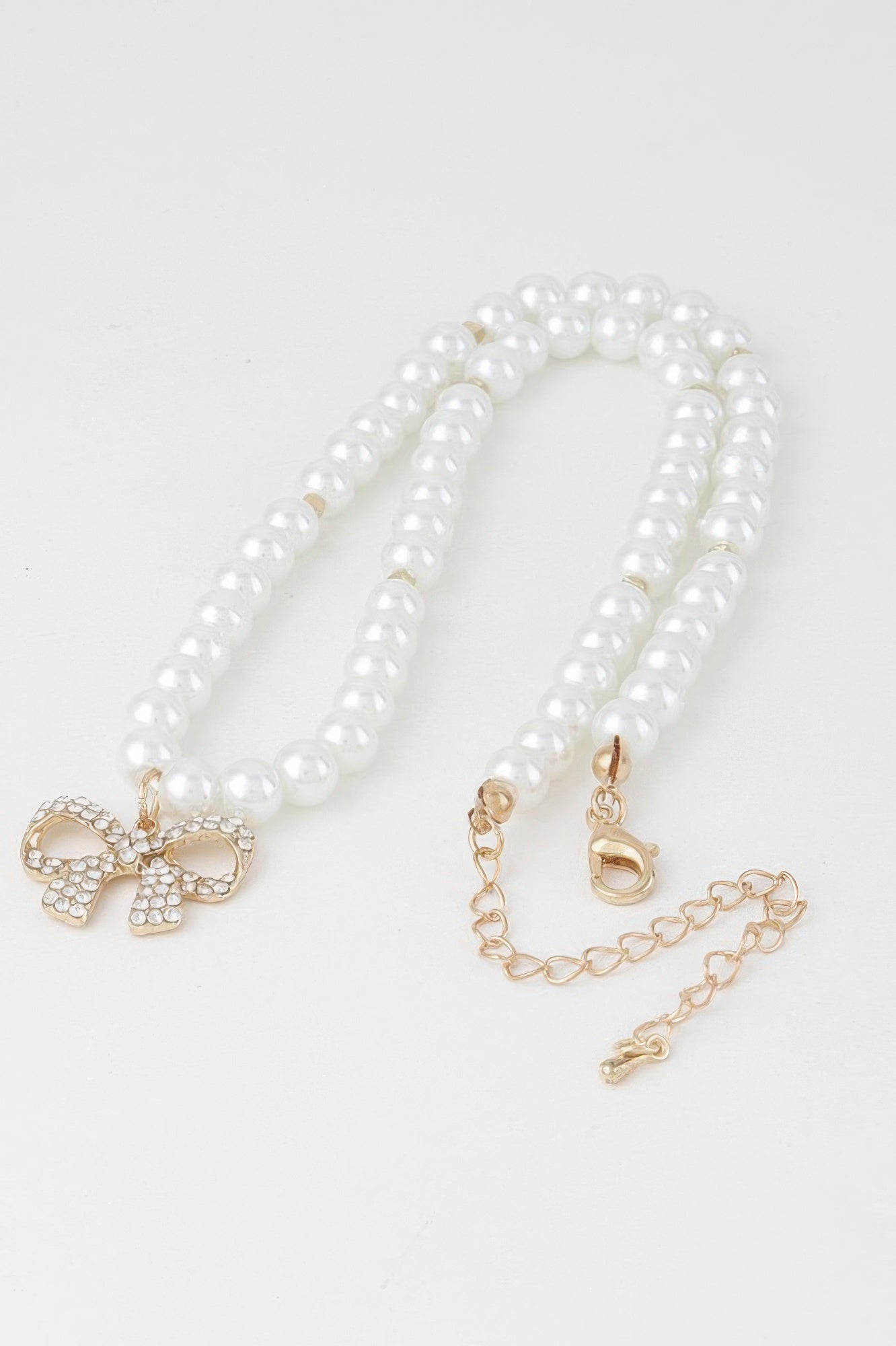 White pearl bow necklace set with pearl strands, gold-tone bow charm and clasp