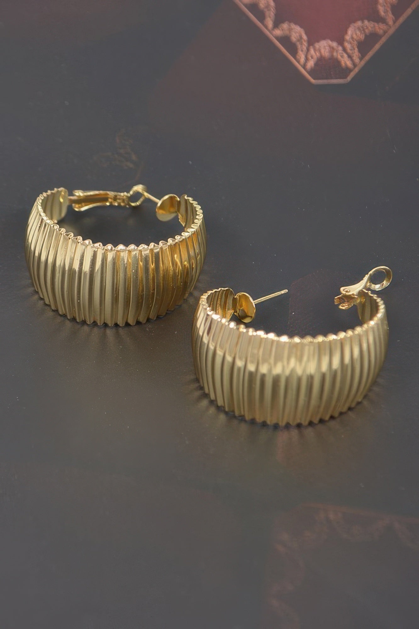 Wide gold metal hoop earrings, ridged texture with clasp backs