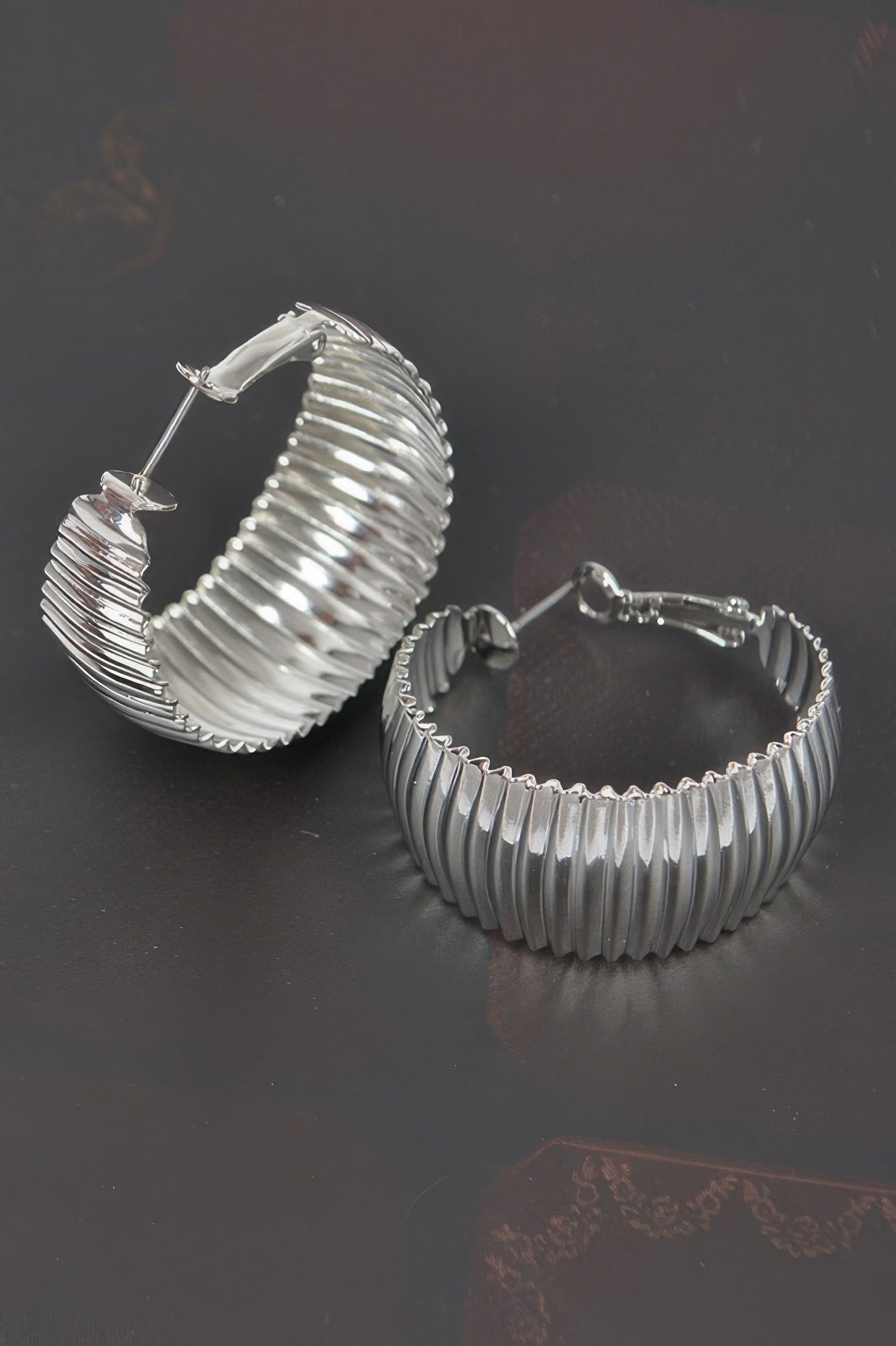 Wide silver metal hoop earrings with ridged semicircle profile