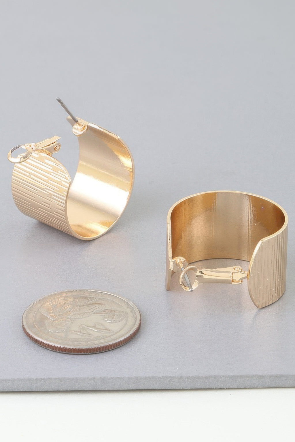 Gold wide ribbed hoop earrings with clasp, close-up of textured metal hoops