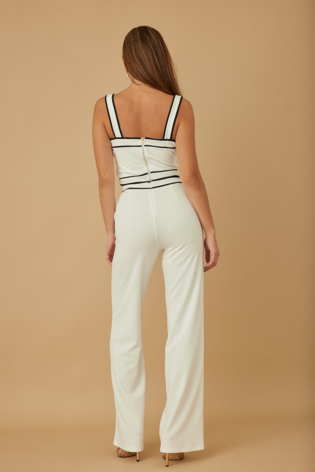 Back view of contrast white two-piece: black-trimmed straps with back seam on wide-leg pants