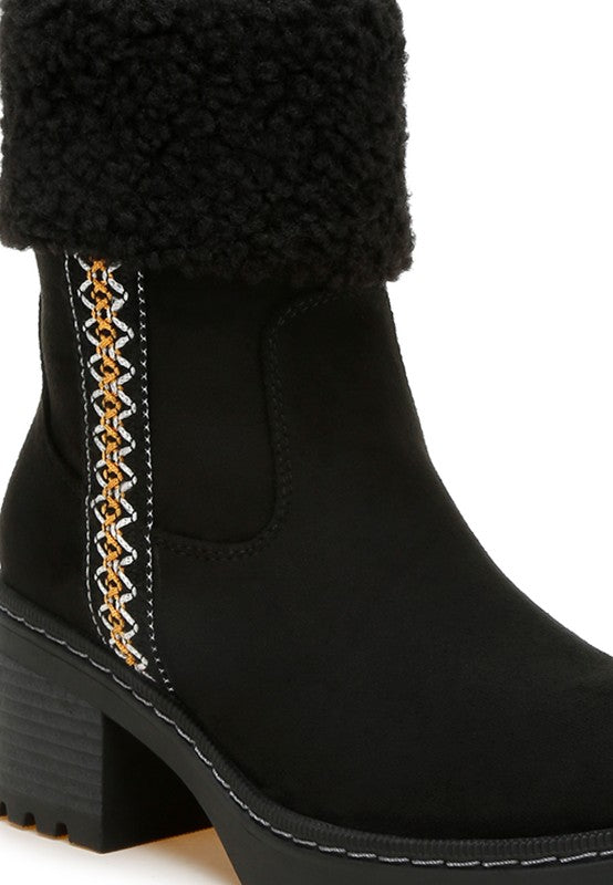 Black boot close-up with embroidered vertical strap, faux fur cuff, and side pull tab