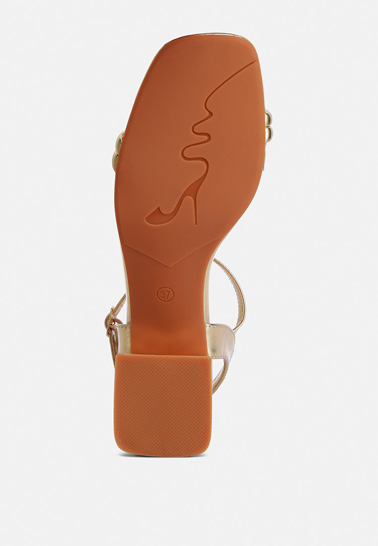 Heel outsole view with engraved logo from an open square-toe ankle-strap sandal