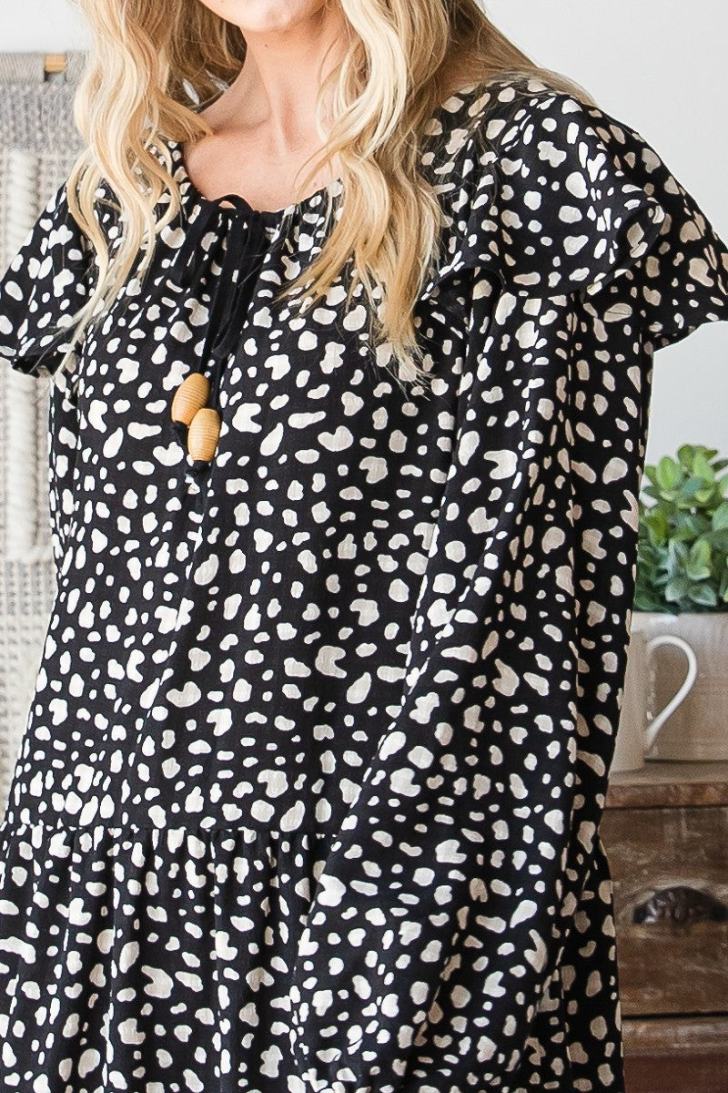 Front close-up: black maxi dress with white abstract heart print and tie neckline