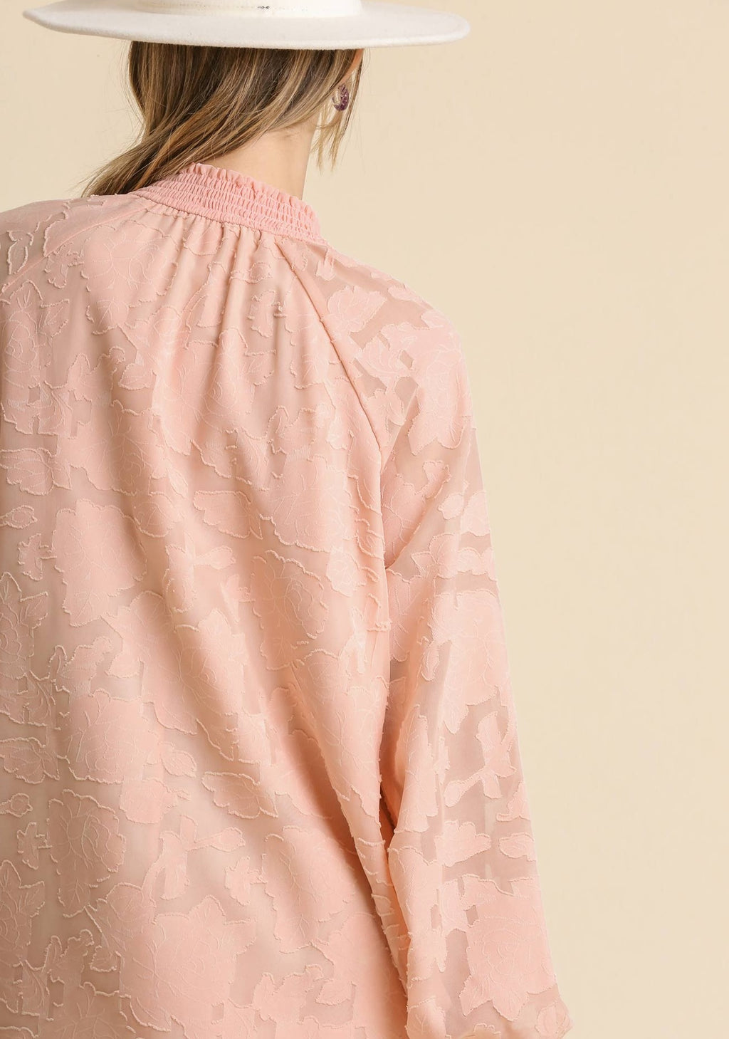 Back view of blush jacquard dress with long raglan sleeves and smocked yoke
