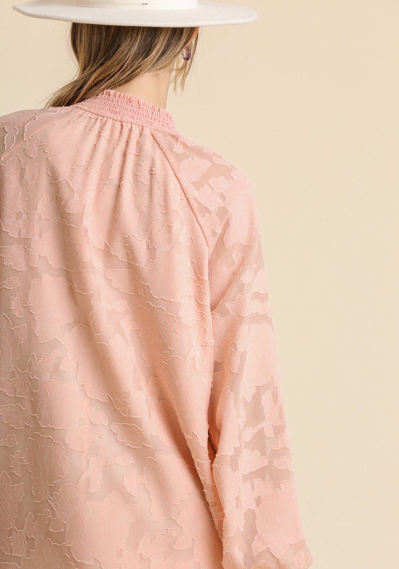 Back view of blush jacquard dress with long raglan sleeves and smocked yoke