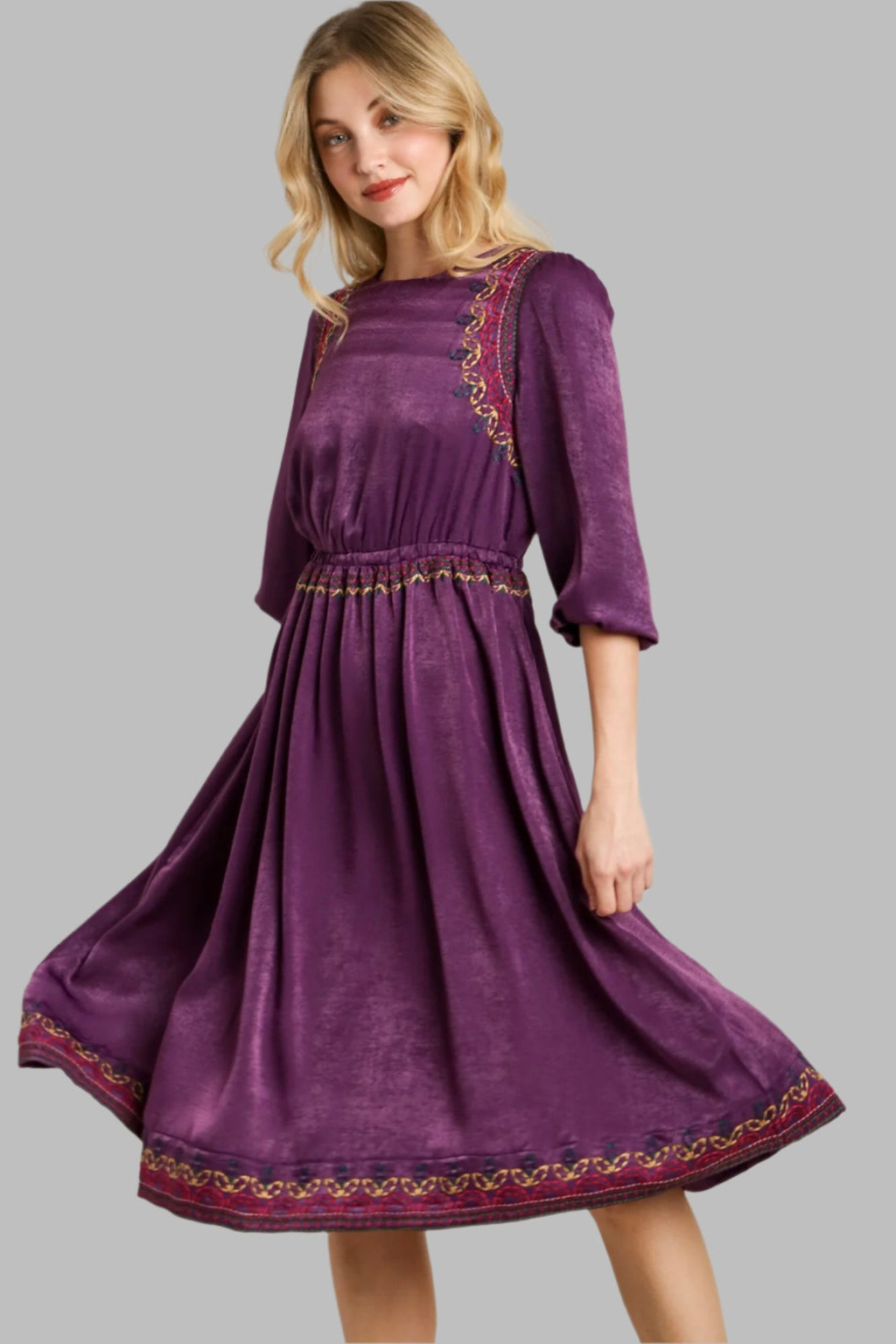 Purple satin midi dress side view, gold-trimmed yoke and flared hem with embroidery