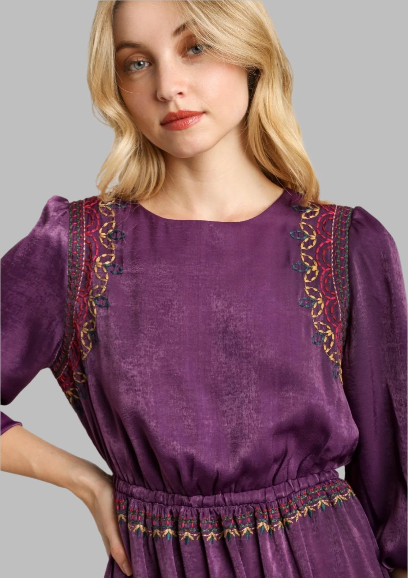 Purple satin round-neck dress close-up with gold and red embroidered shoulder trim