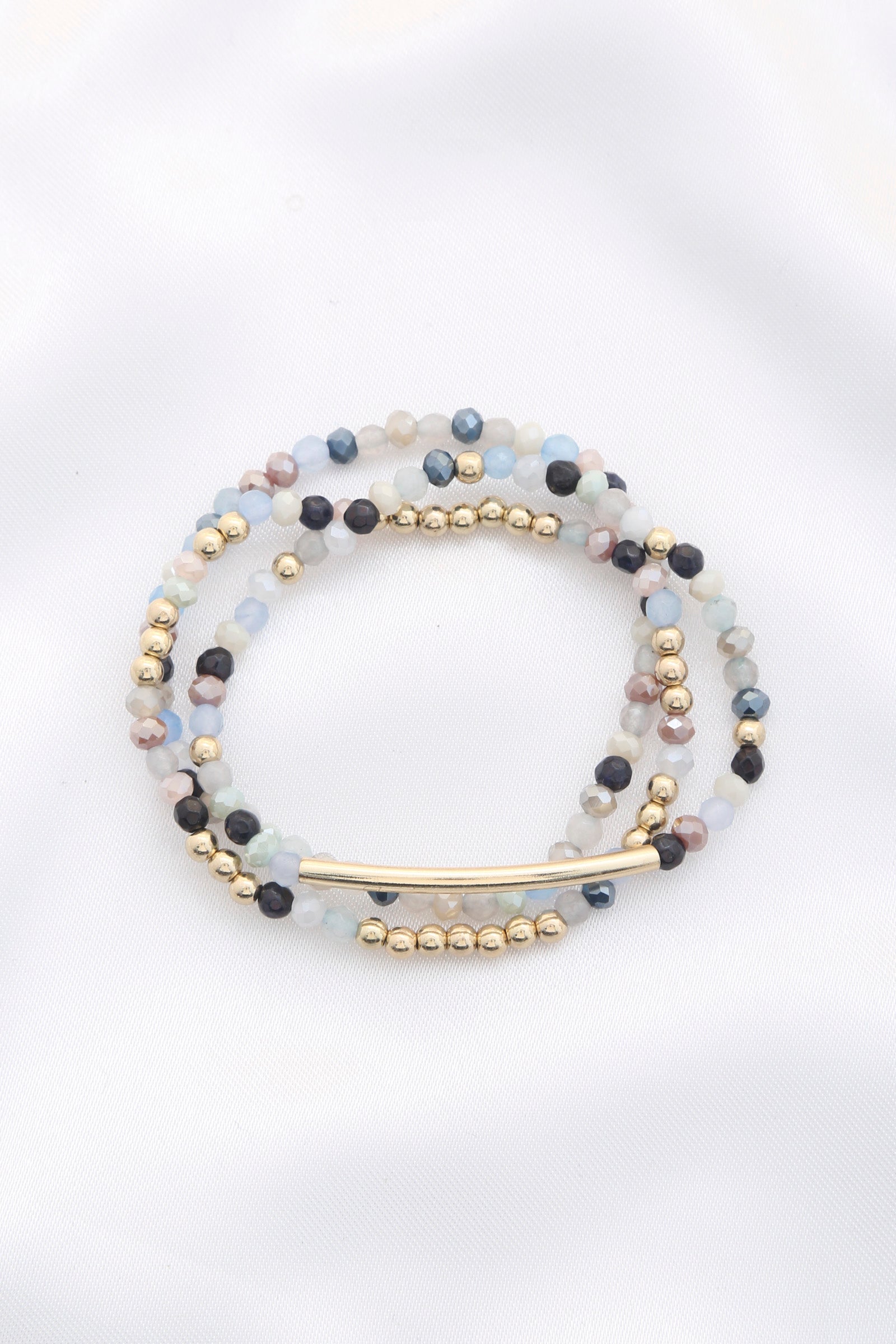 3-row stretch bracelet with blue, clear, and black glass beads; gold bar and spacers