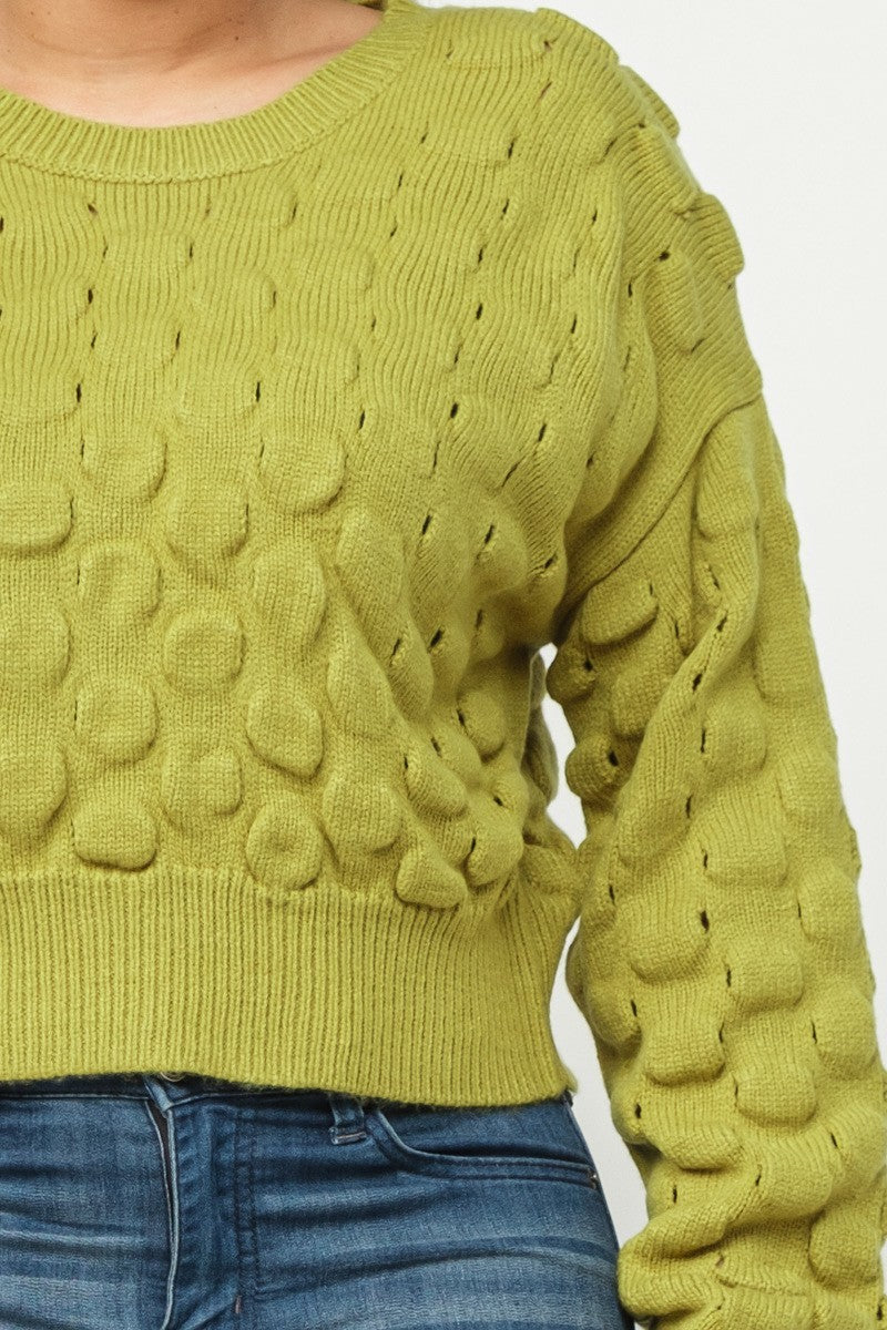 Close-up of lime green checker-knit sweater texture on long sleeve