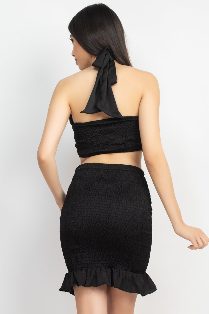 Vista trasera: top halter cruzado negro y falda corta fruncida con volante