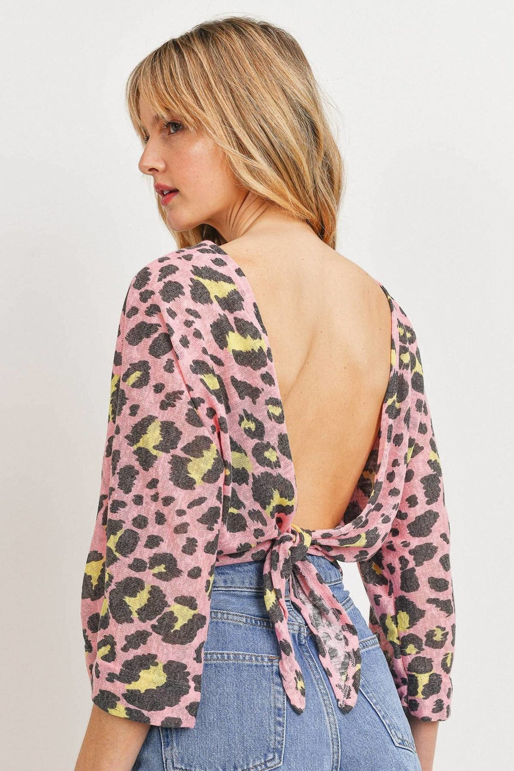 Open-back pink leopard print knit top, tied bow at lower back, three-quarter sleeves