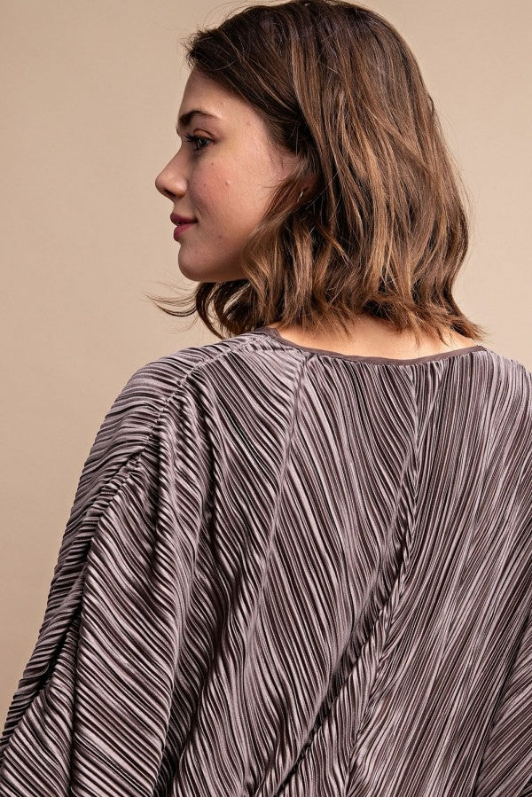 Back of silvery pleated satin top with long sleeves and V-back drape
