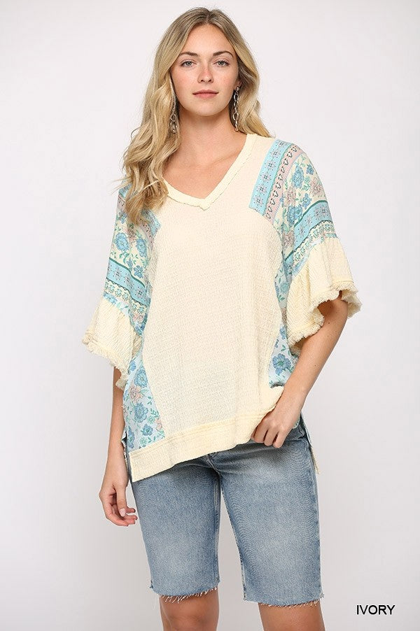Ivory knit top with printed sleeves, V-neck and ruffle cuff detail, hi-low hem