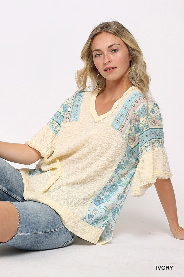 Ivory knit top with printed sleeves, V-neck, and slightly longer hi-low back